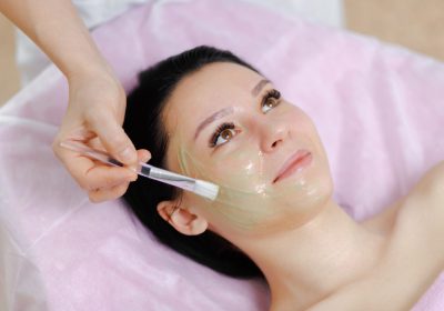 Young beautiful girl with dark hair gets procedure with collagen mask in a beauty salon. Face Skin Care. Cleansing Procedure. Cosmetology.